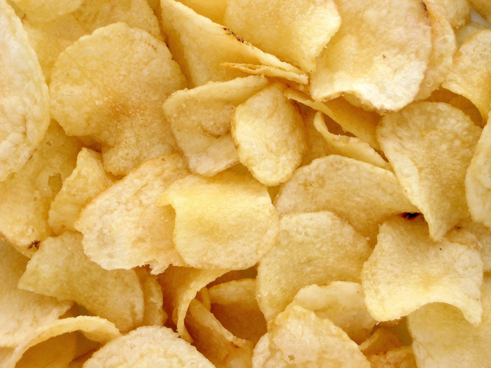 A close-up pile of plain salted potato chips filling the whole frame