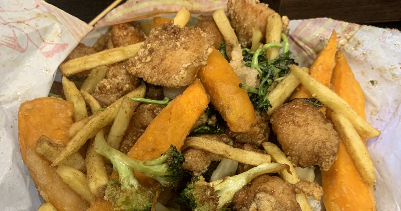 A Taiwanese fried chicken basket on wax paper: popcorn chicken, french fries, sweet potato fries and fried broccoli tossed together